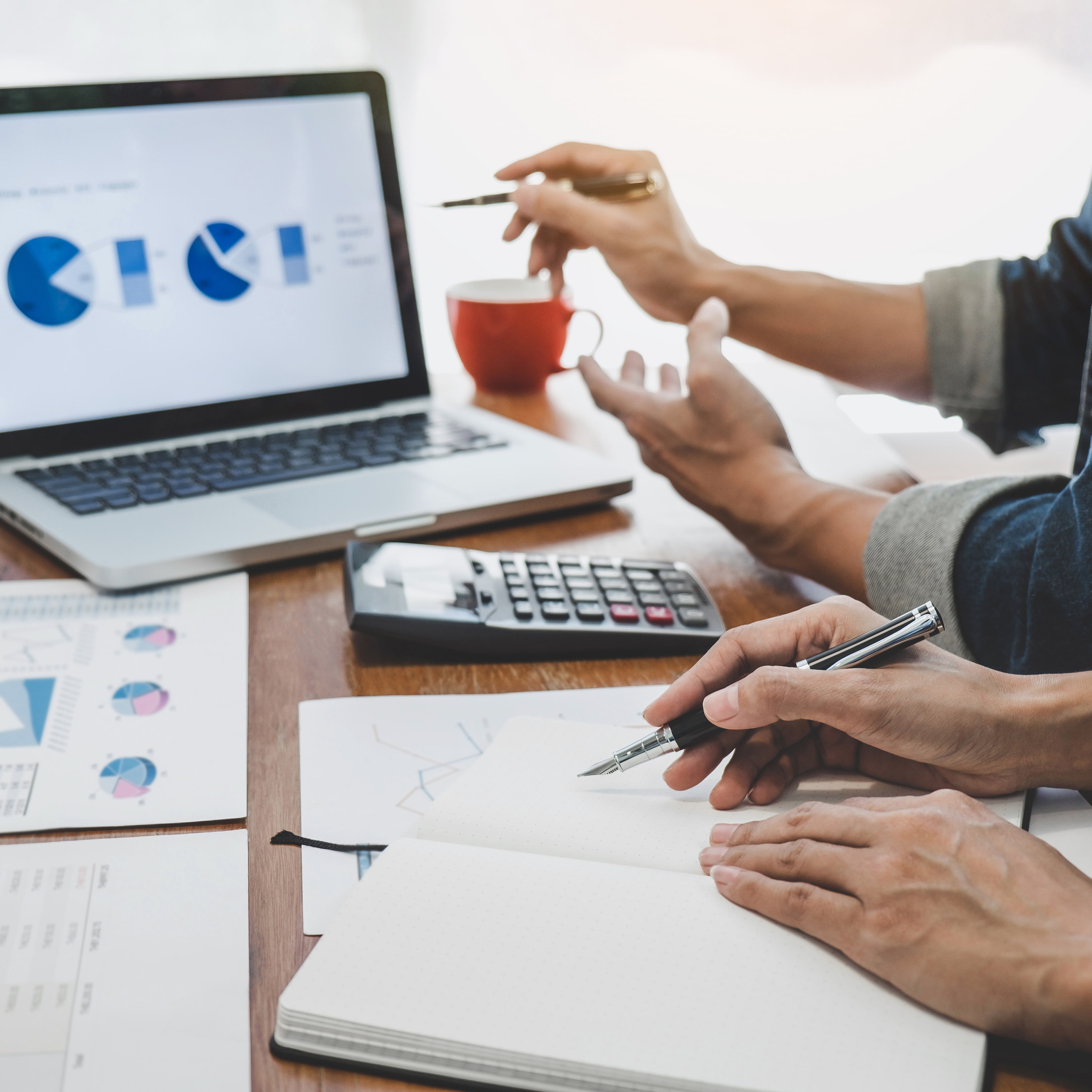 Reunión de asesoría fiscal en Madrid con empresarios y autónomos revisando documentos y gráficos financieros en una oficina moderna.